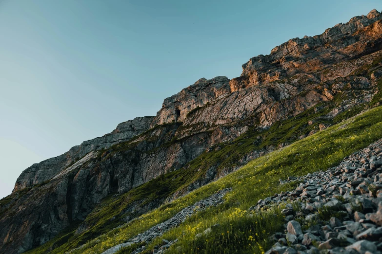 the top of the mountain is covered in rocks and green grass