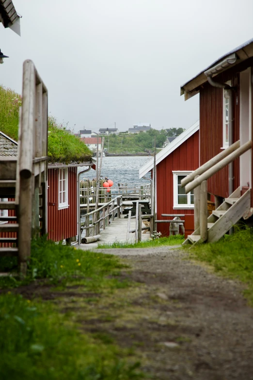 a couple of red wooden buildings sitting next to a body of water