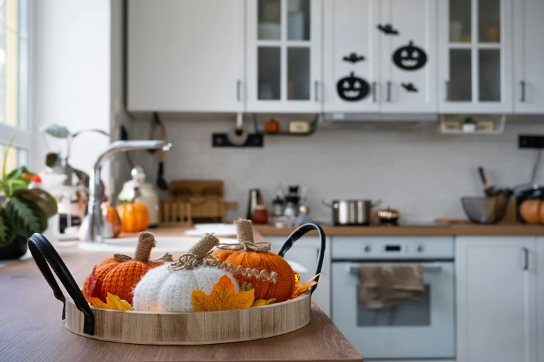 decorative pumpkins in a basket sitting on a kitchen counter