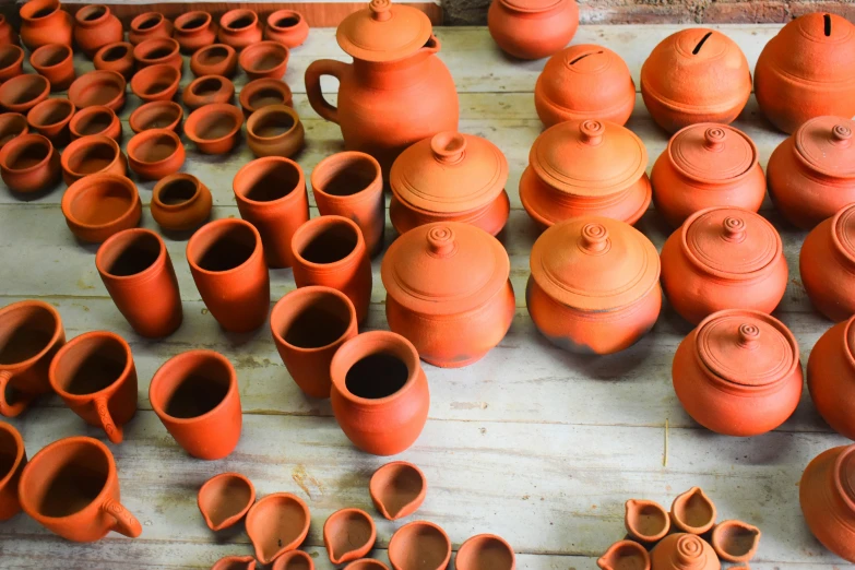 a table topped with orange clay pitchers and jars