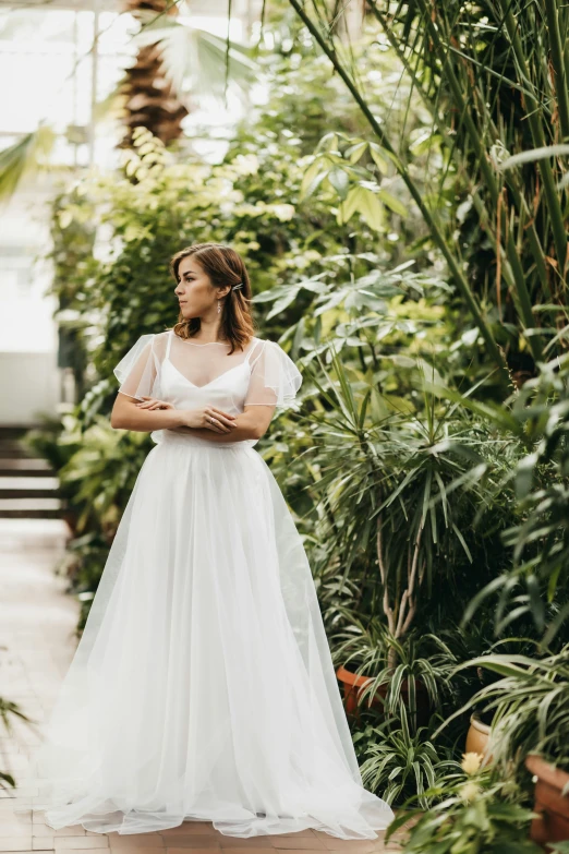the bride stands in the middle of plants in her dress