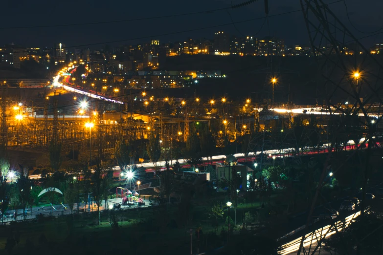 nighttime scene of a city with lights on and a long train in the middle