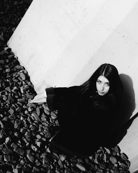 a woman sitting on a rock next to a column