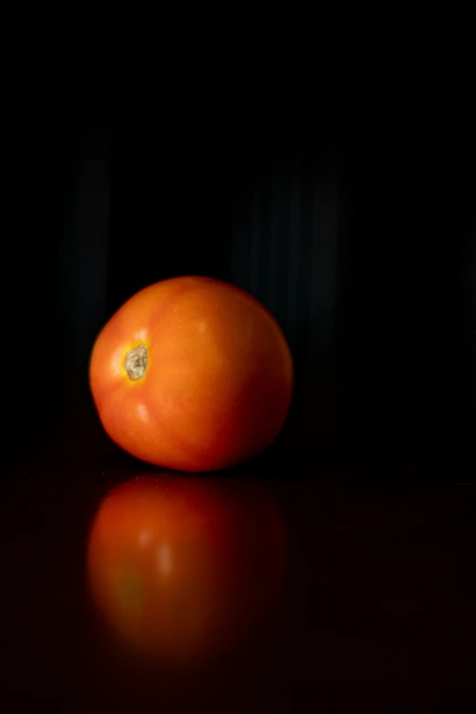 a single orange on a black surface