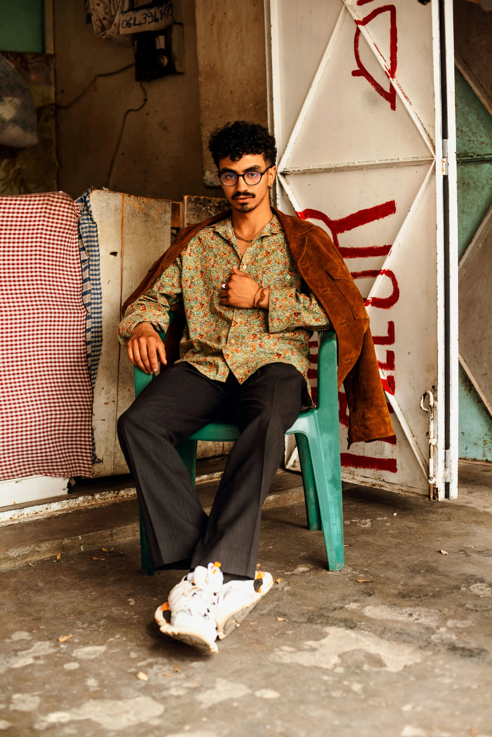 a young man sitting on a green chair next to a skateboard