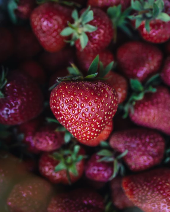 a close up of a red strawberry full of it's tops