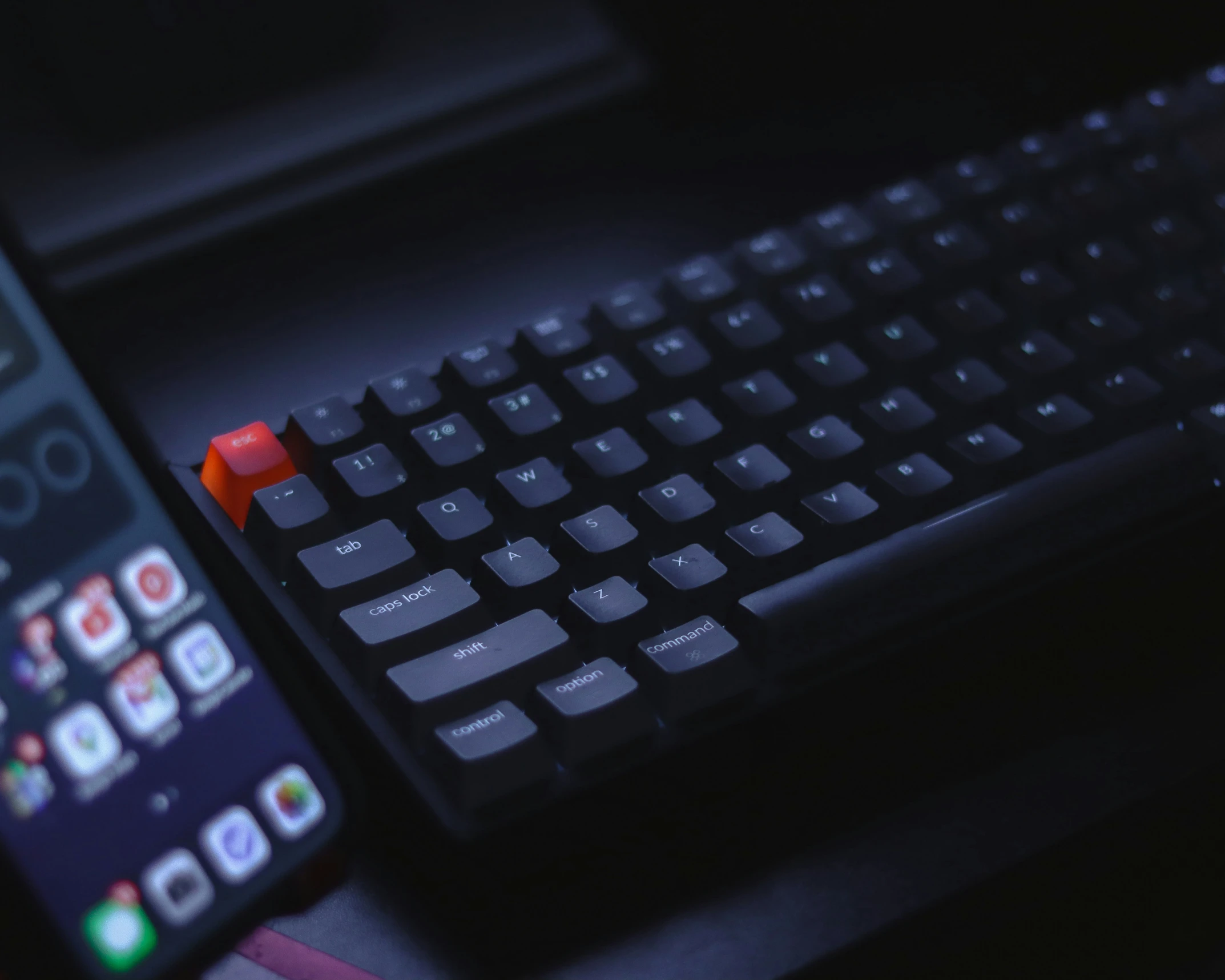 a cellphone sits beside a keyboard that is sitting on a desk