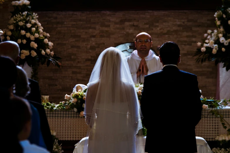 a person in wedding dress standing in front of another person at the alter