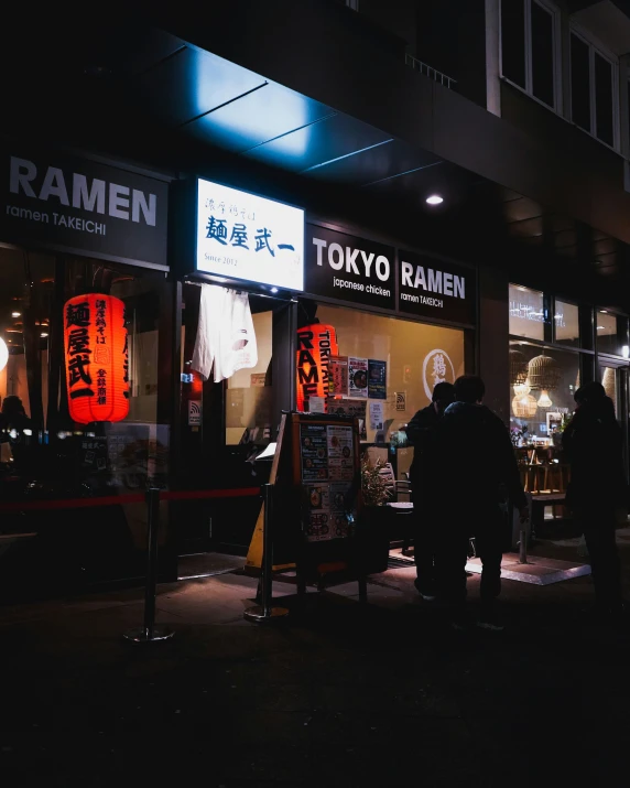 people are standing outside of a store at night