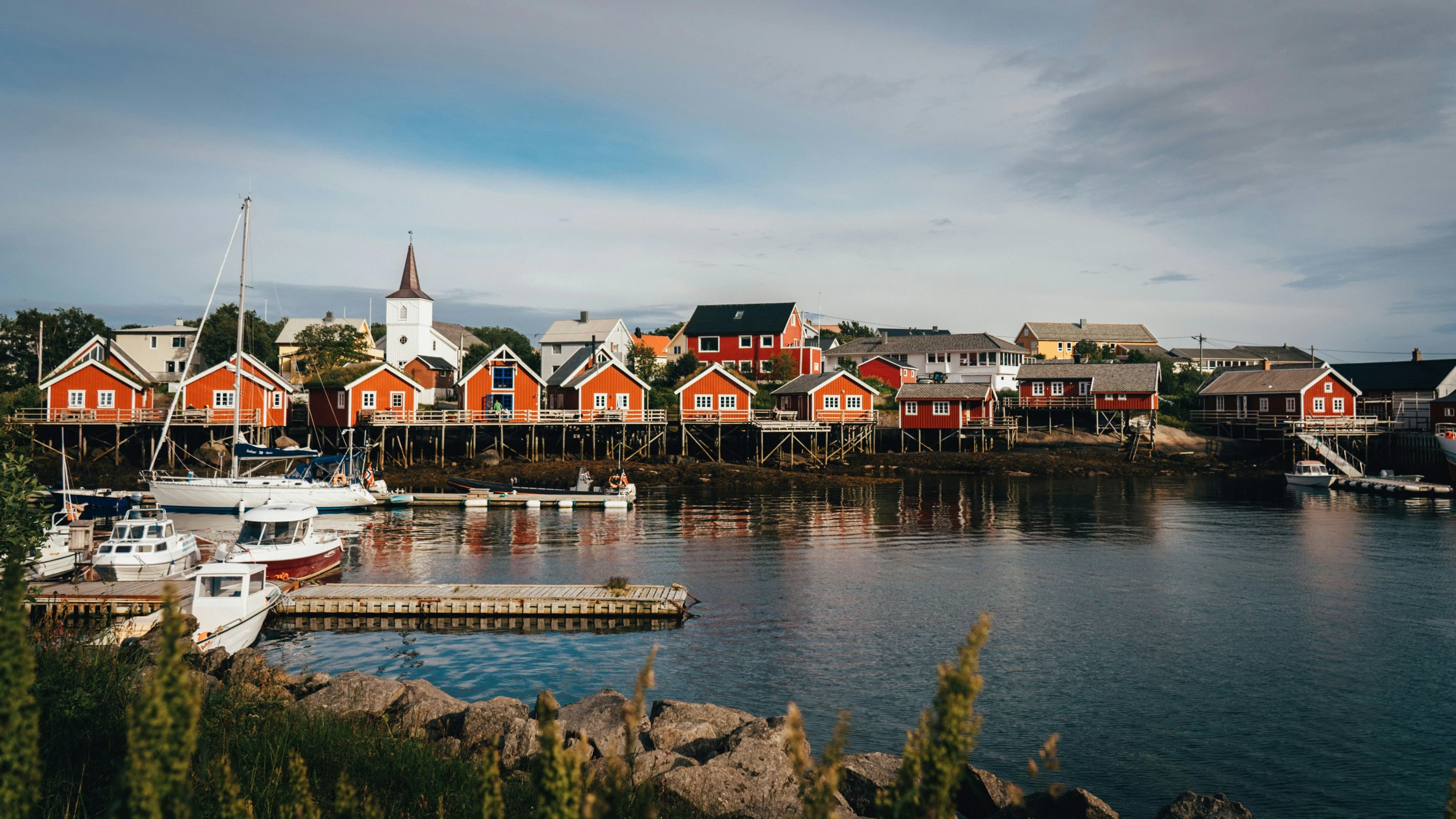 boats are sitting at the dock near some red buildings