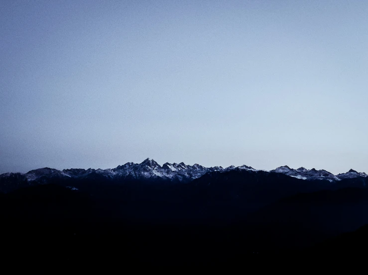 a plane flying above a mountain range in the blue sky