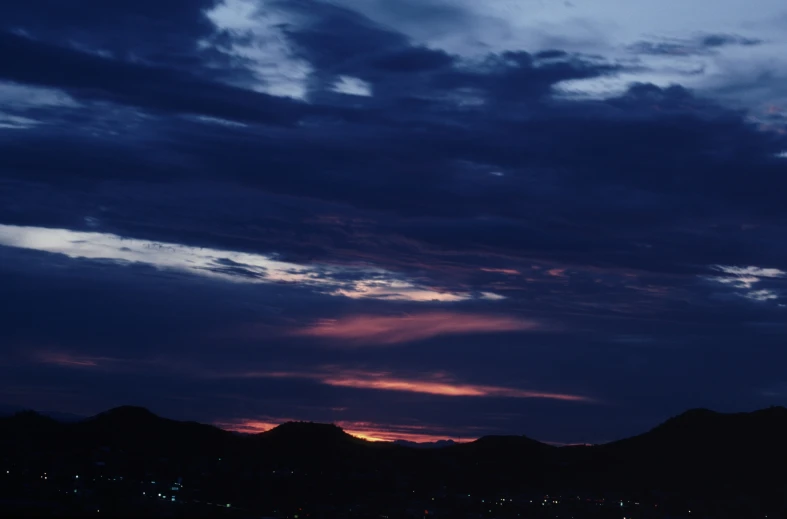 the airplane flies into the dark sky above some mountains