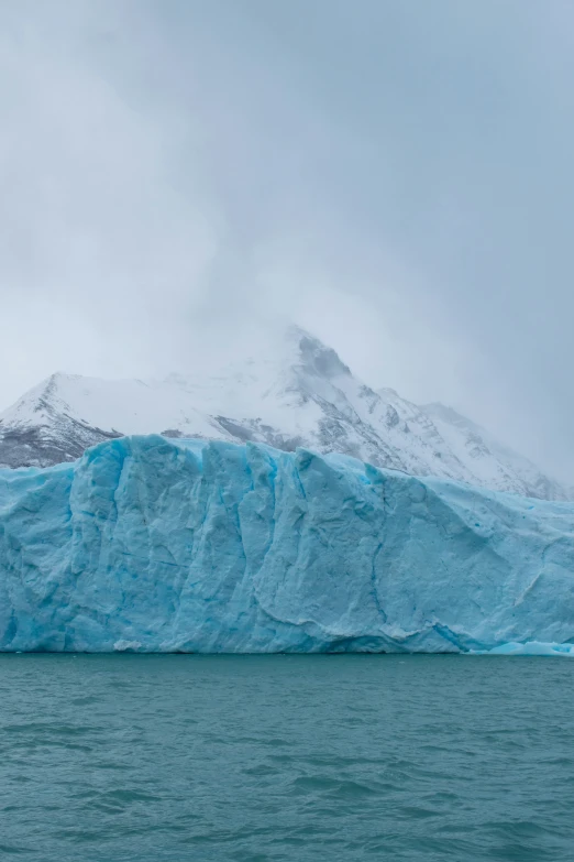 an iceberg with two large snow capped mountains in the background