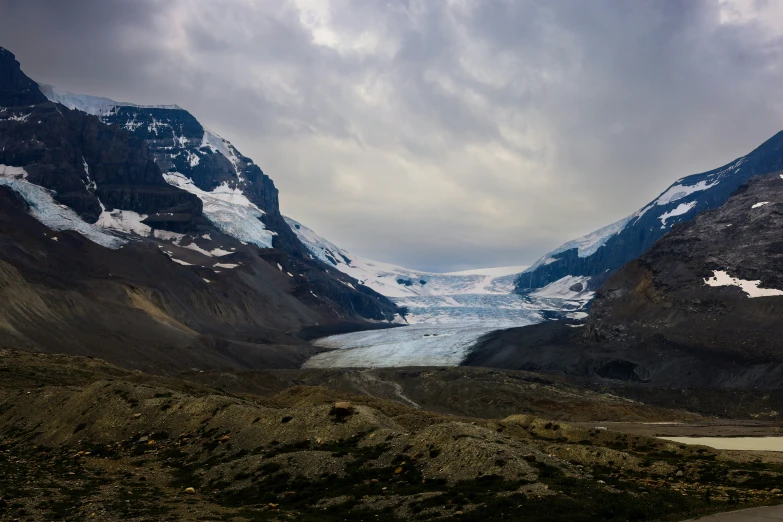 a glacier in the distance with a snowy mountain and ice covered hills behind it