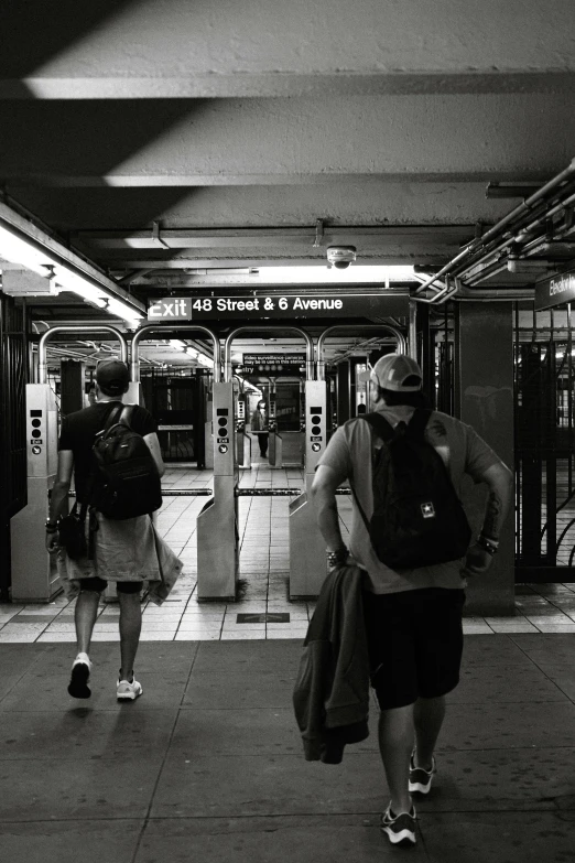 two people with backpacks walk on a sidewalk