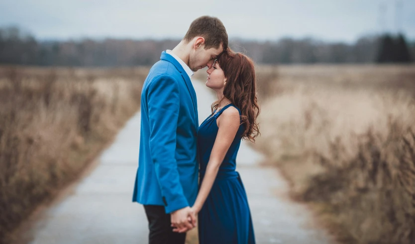 a couple is kissing while standing in a field