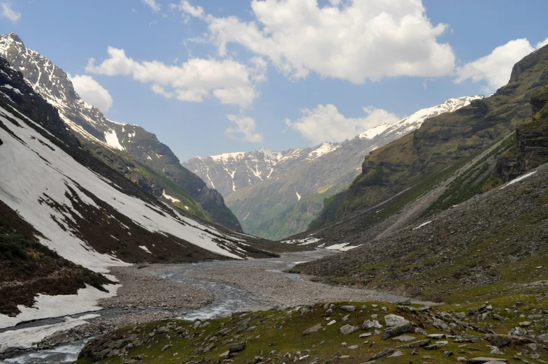 a mountain valley is surrounded by snow and grass