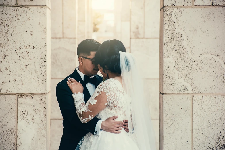 a bride and groom in front of an old wall