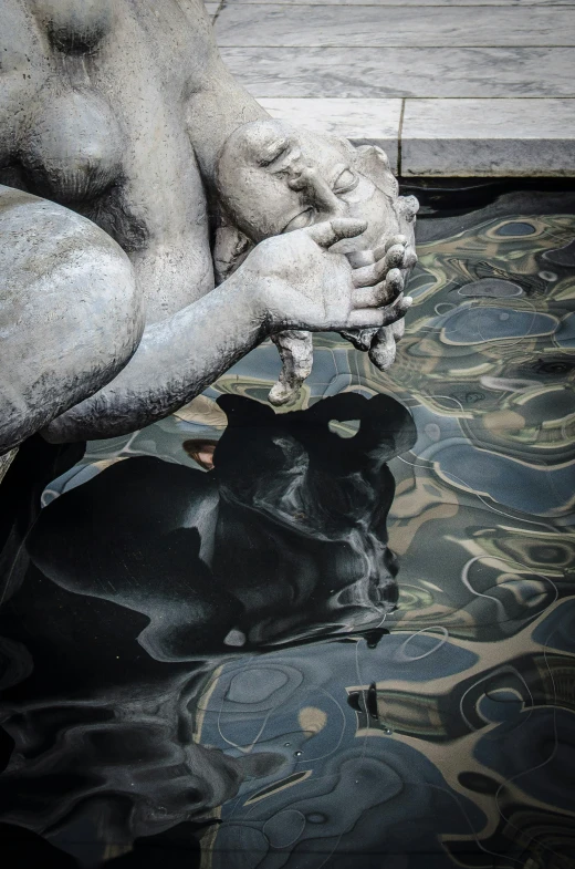 a dog sleeping in the water next to an artistic statue