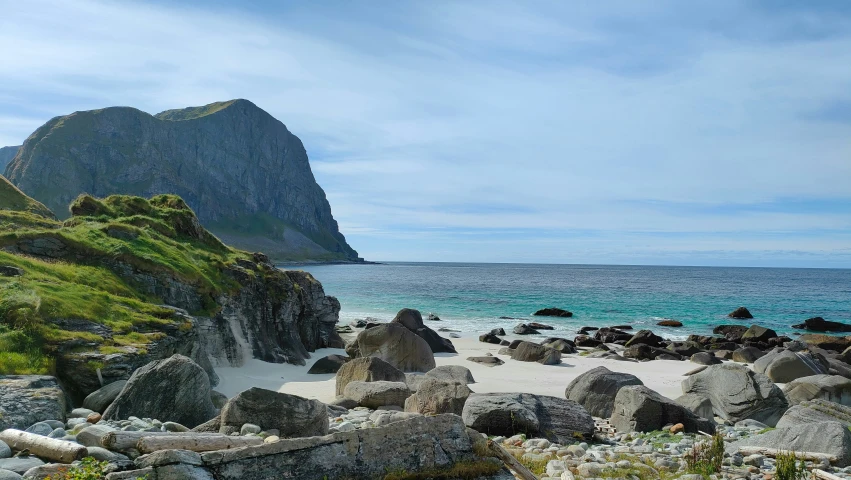 a sandy beach next to a mountain with water