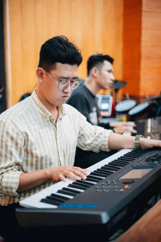 two people sitting in front of an electronic keyboard