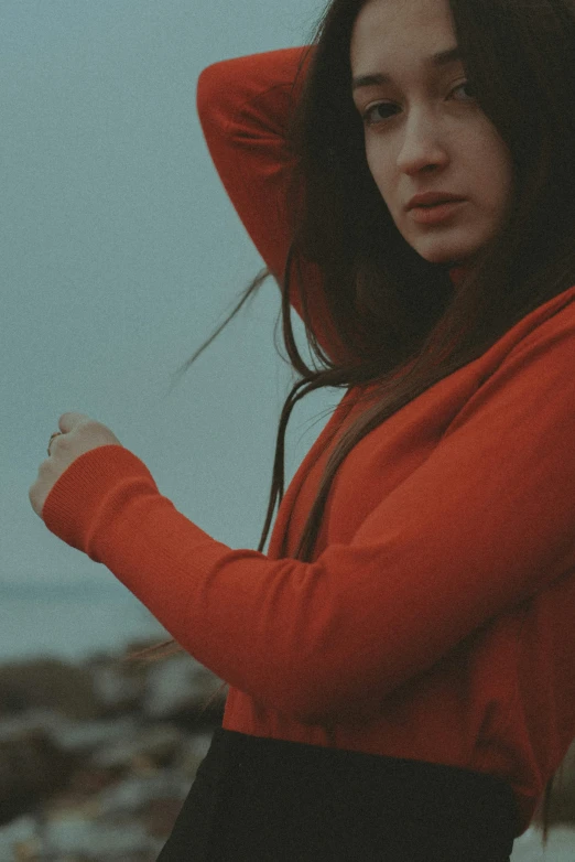 a woman wearing an orange hoodie poses on the rocks