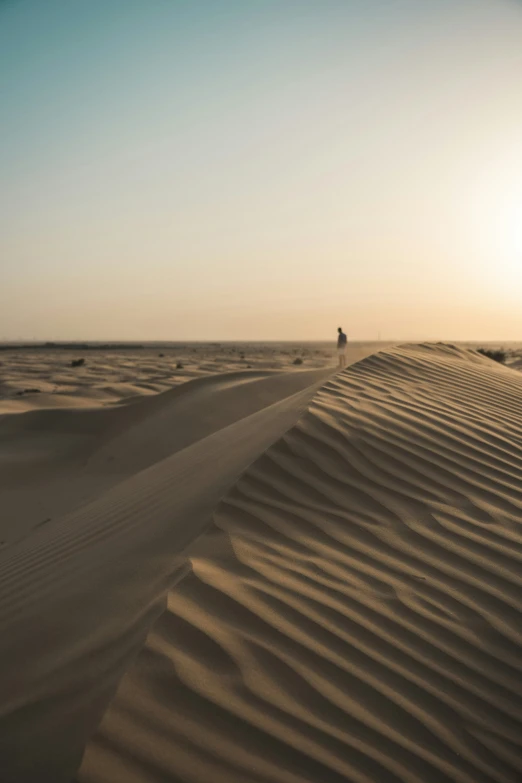 a man stands in the sand dunes watching the sun go down