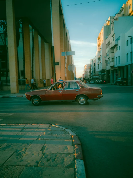 the old red car is driving down the street