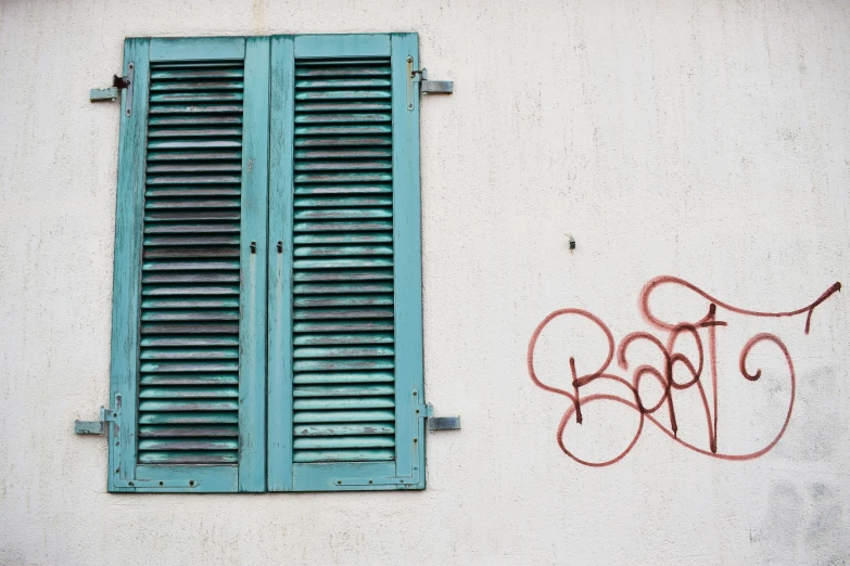 there is a wall with a window and blue shutters on it