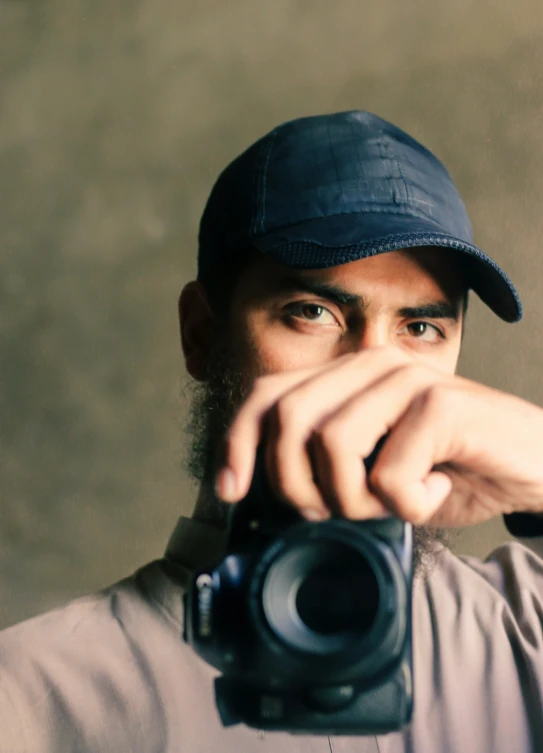 a man wearing a baseball cap taking pictures with a camera