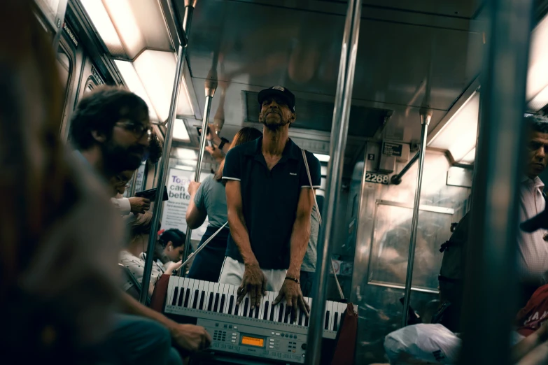 a man standing on a crowded subway train holding a piano