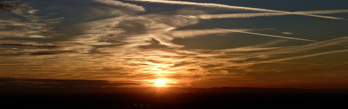 an image of the sun setting with contrails coming out