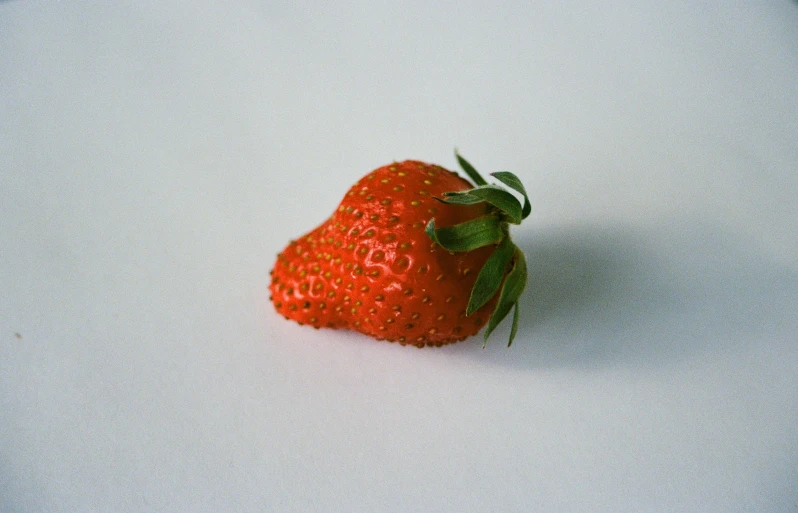 a single strawberry is laying down in the snow