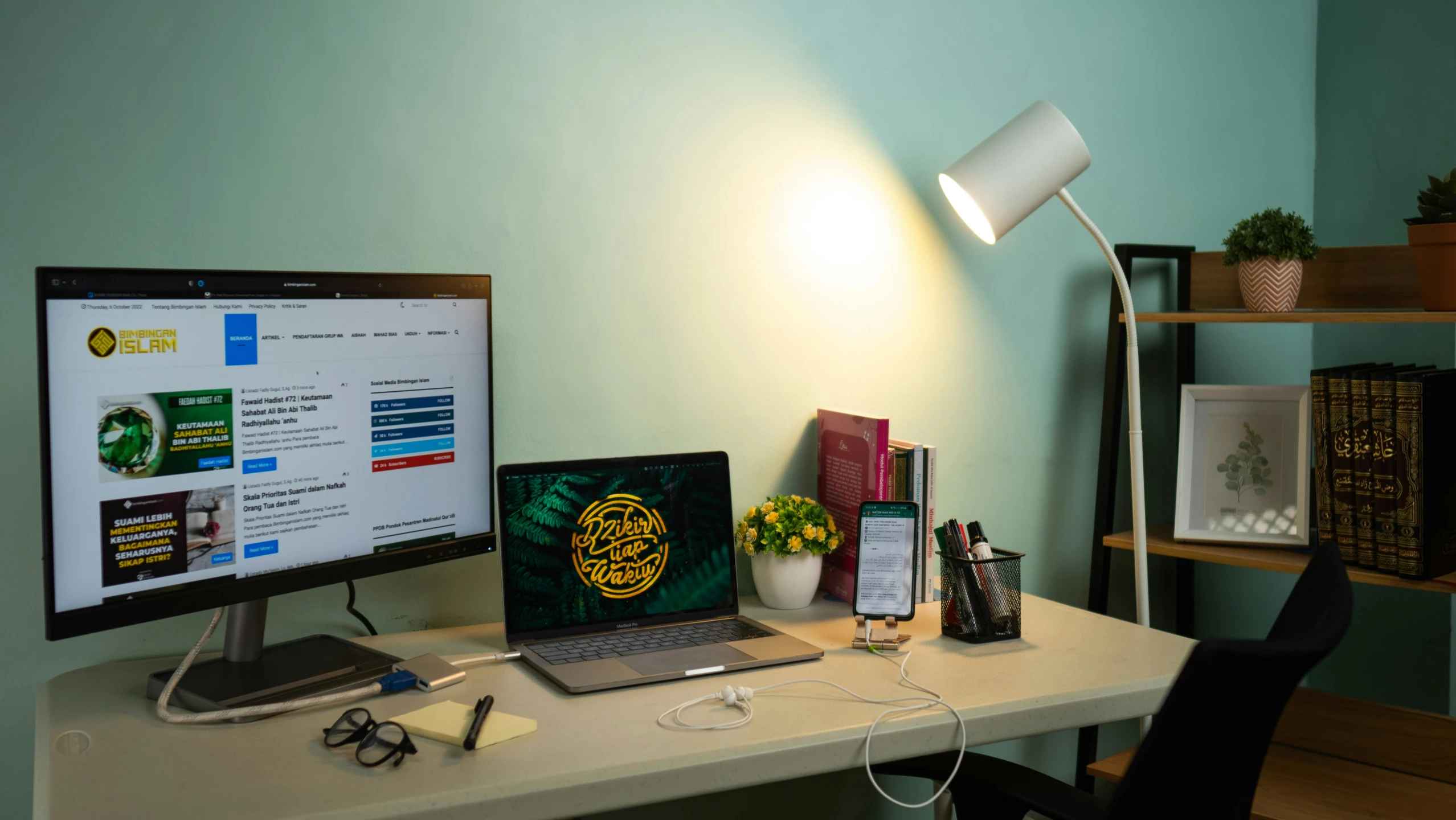 a desk with a computer, phone, and books