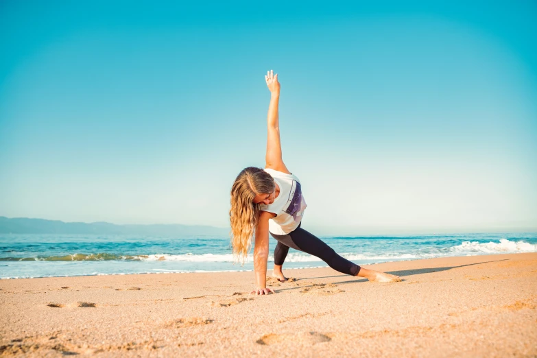 a person bending over in the sand with their arm raised