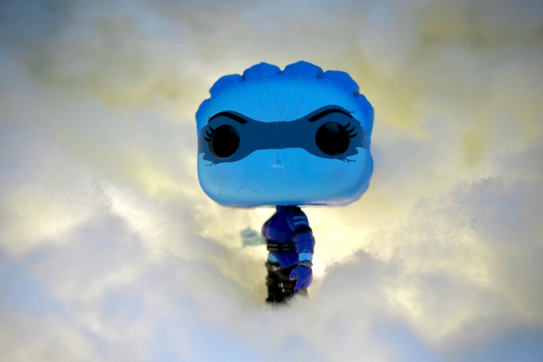 a blue pop vinyl figure stands on a cloud background