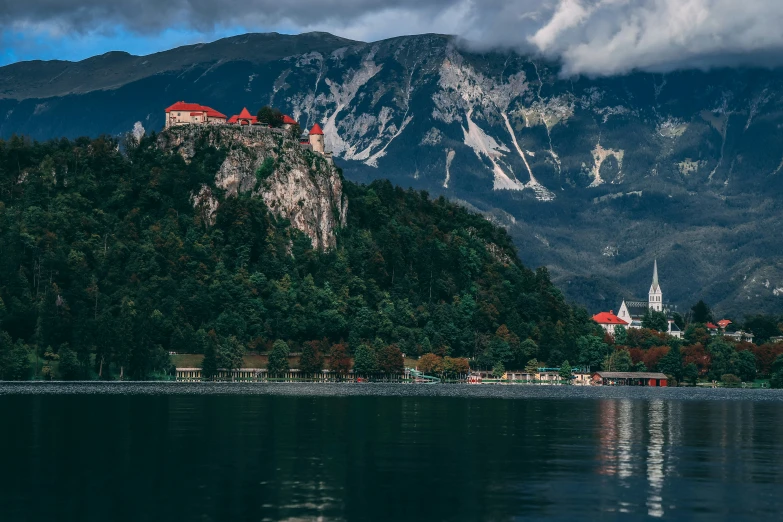 an island sits on the shore of a body of water with mountains in the background