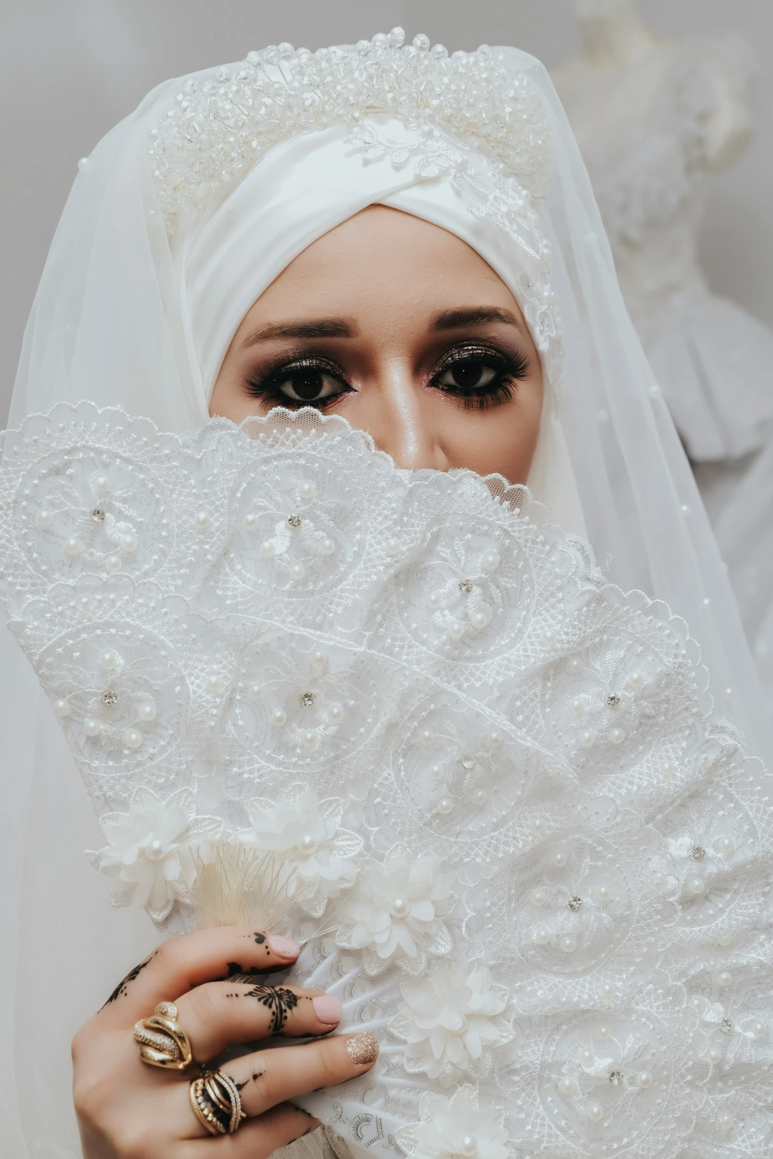 a woman in white veils and gold jewelry covering her eyes