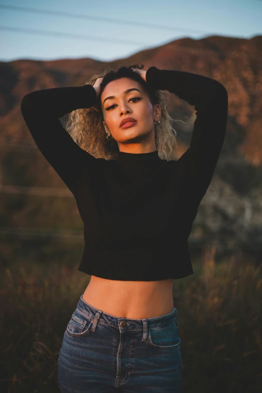 a woman is posing with her hands behind her head