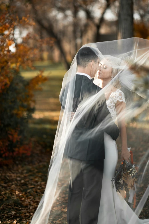 a couple kissing under a veil together in a park