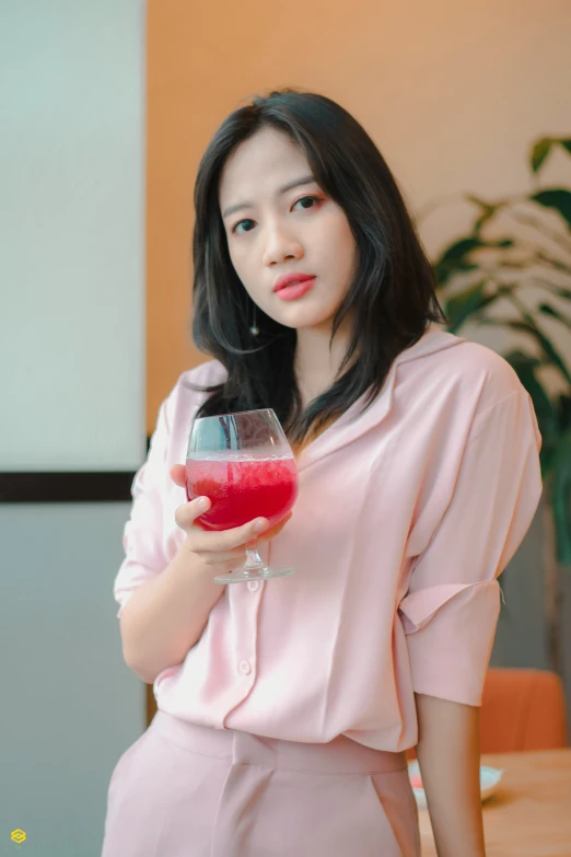 woman in pink top holding a glass of red juice