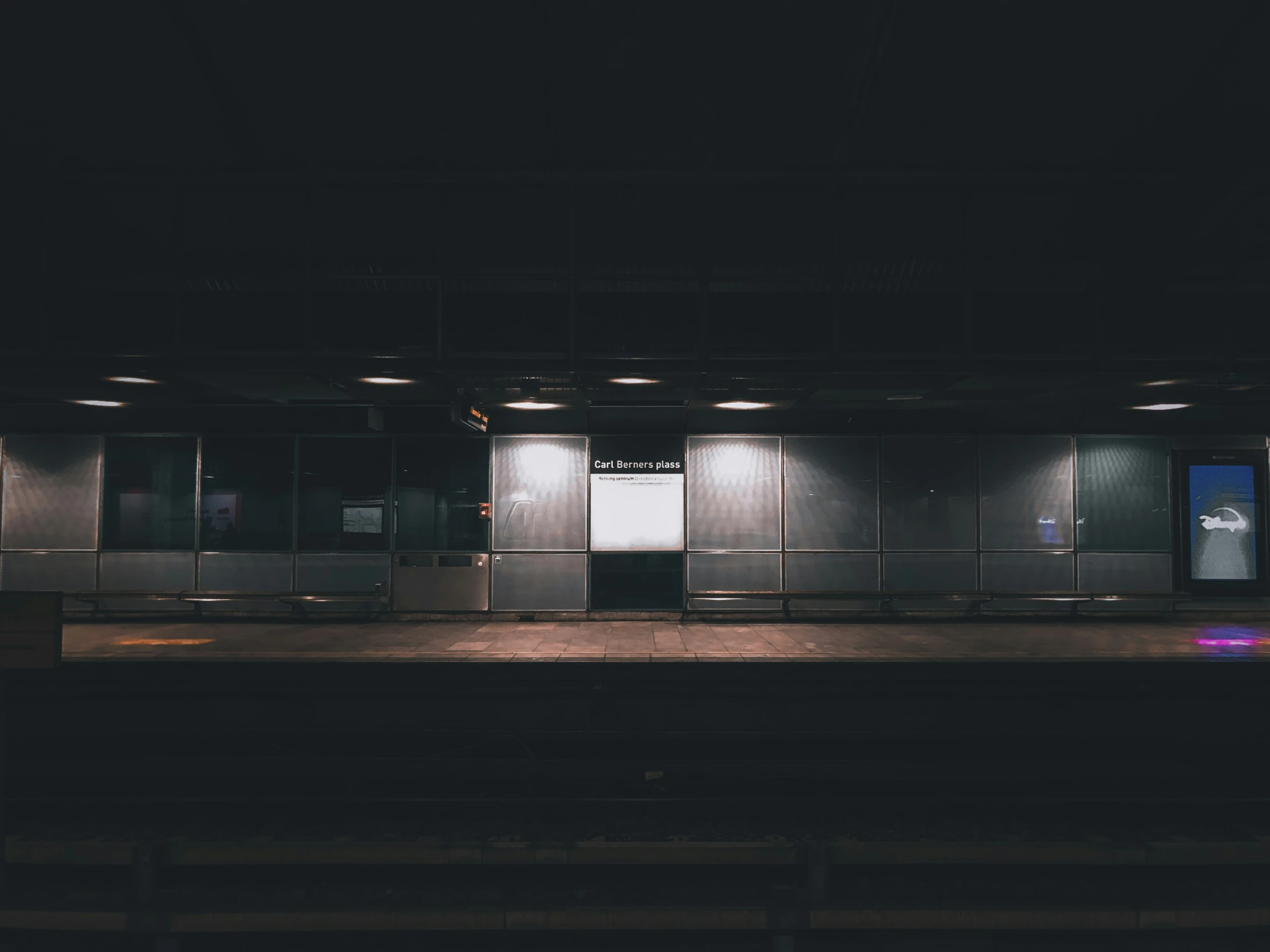 a darkened subway station with benches and elevators