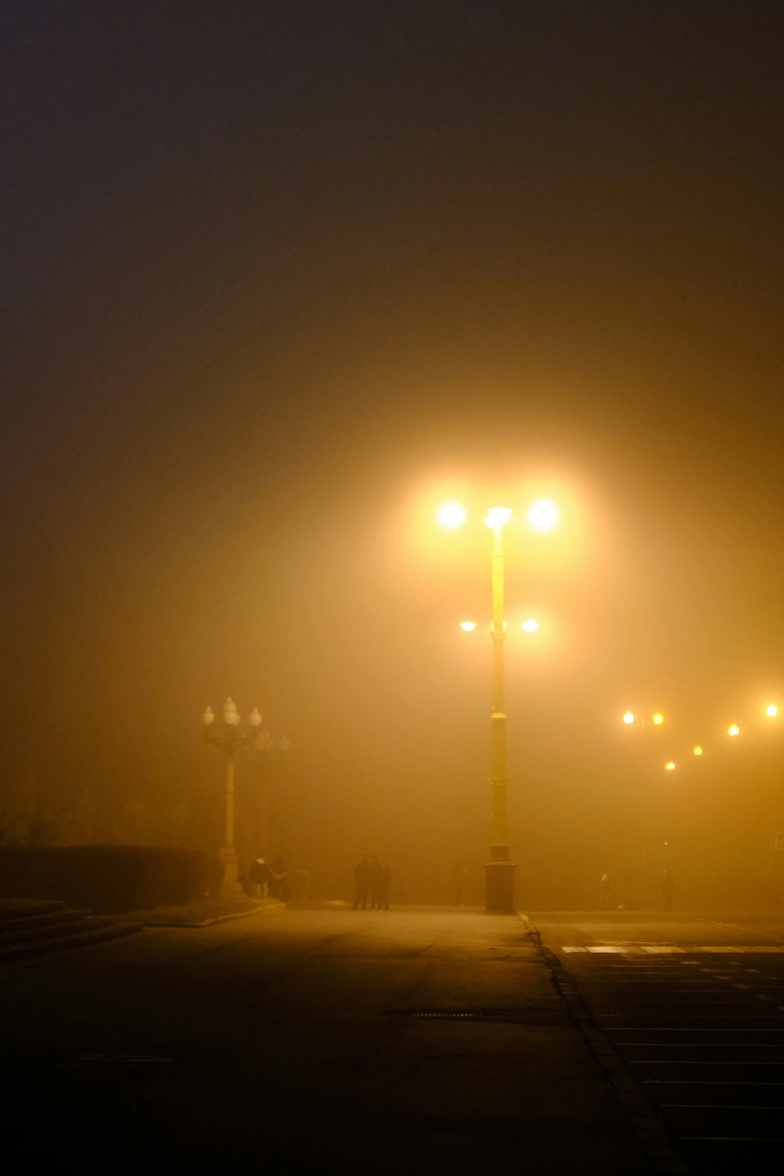 a dark street at night with street lights lit up in the fog