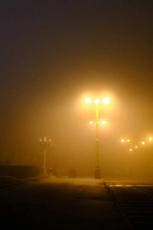 a dark street at night with street lights lit up in the fog