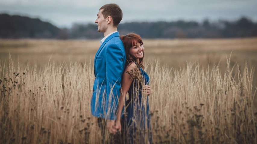 a couple standing next to each other in a field