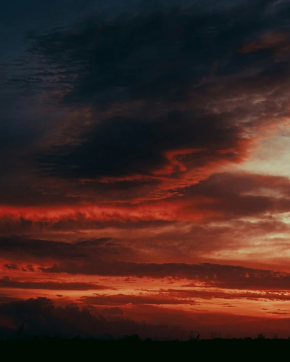 red and blue sunset on a field with clouds in the background