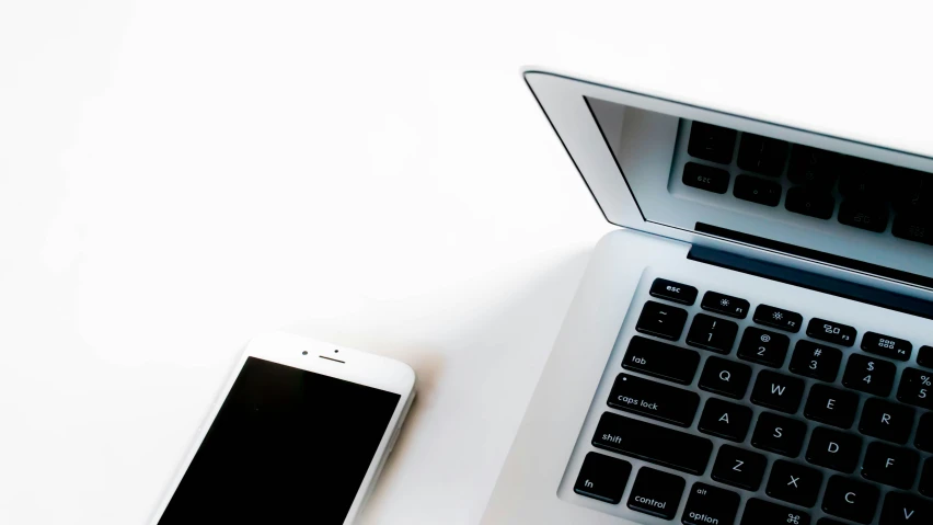 a laptop computer and cellphone sitting on a desk