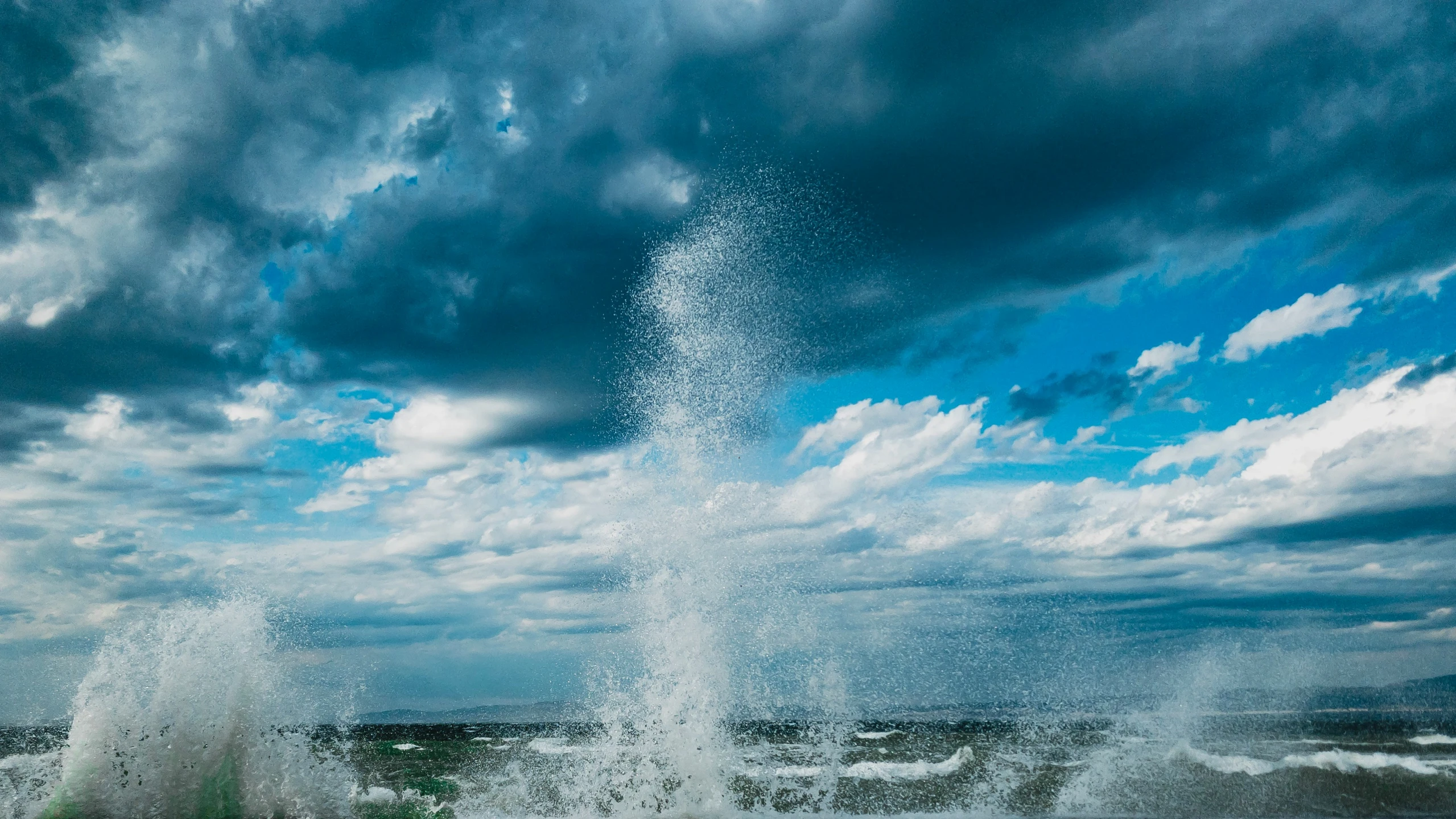 a spray of water crashing onto a green, grassy area