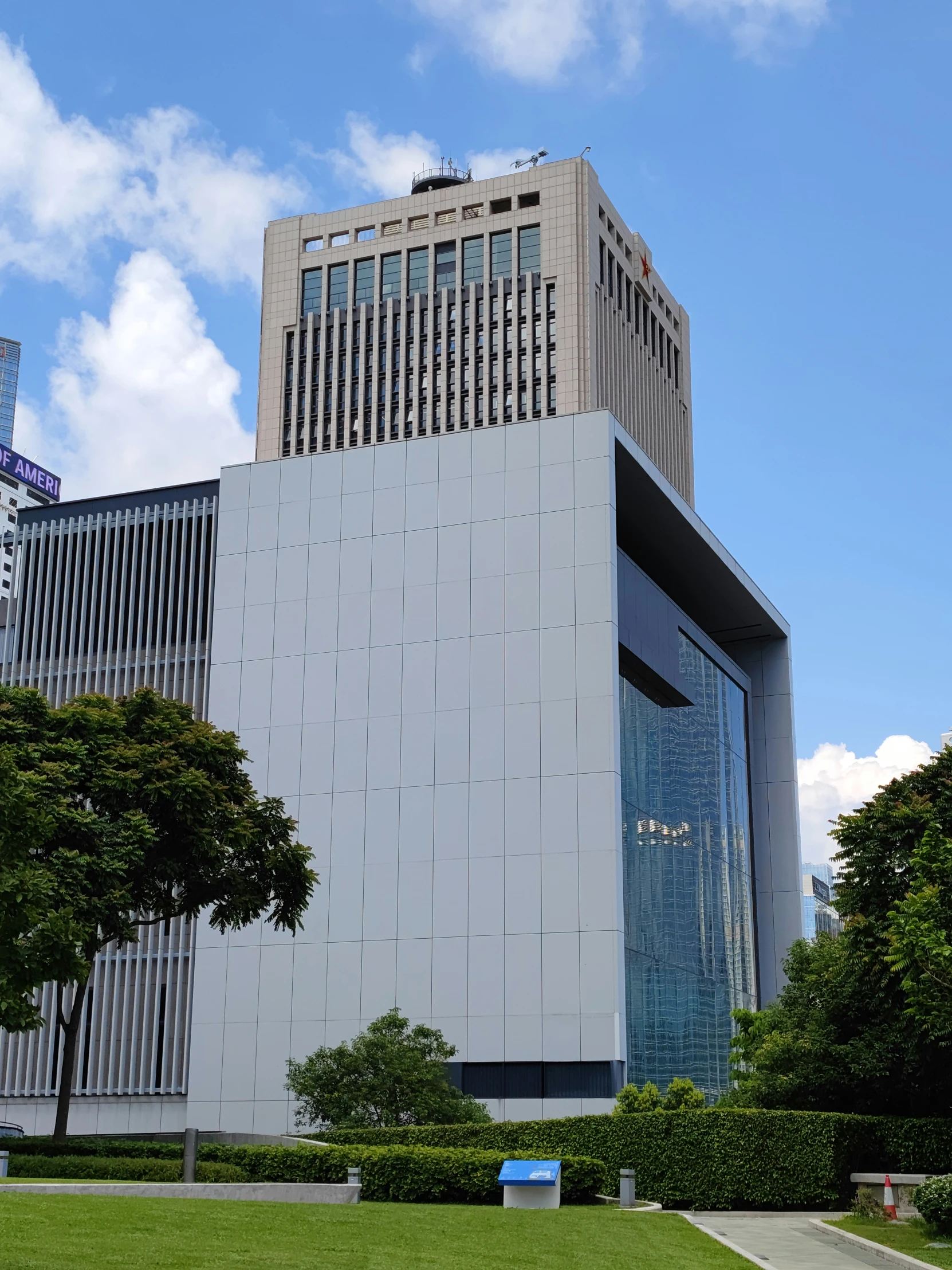 a white building with trees and shrubs in front