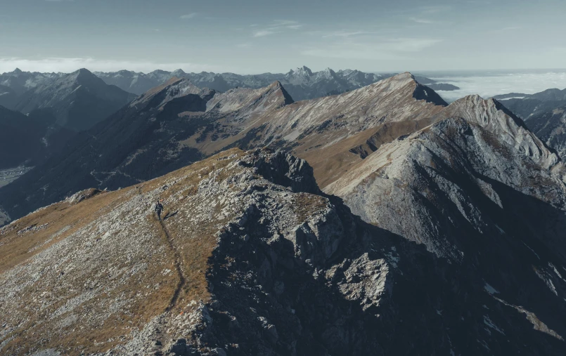 mountain tops are surrounded by brown colored grass